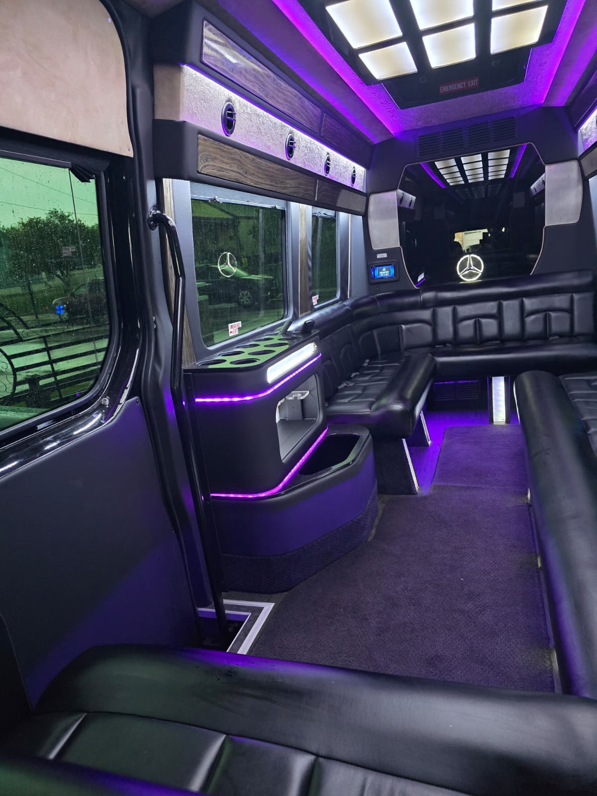 Party bus interior with purple LED ambient lighting and black leather seating